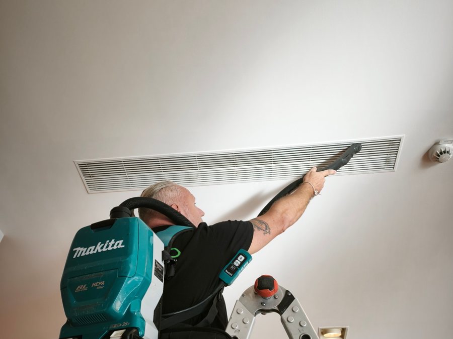 Facilitoo technician cleaning an HVAC grille